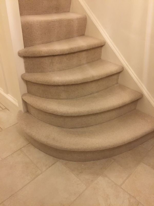 Pale carpet Shaun fitted down curved stairs to a stone-tiled hall in Minchinhampton